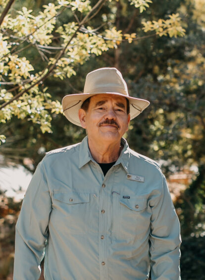 man with blue collard shirt and wide brimmed hat