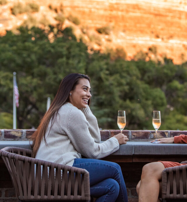 Two ladies smiling at each other as they enjoy their white wine on the patio of Che Ah Chi in Sedona, AZ