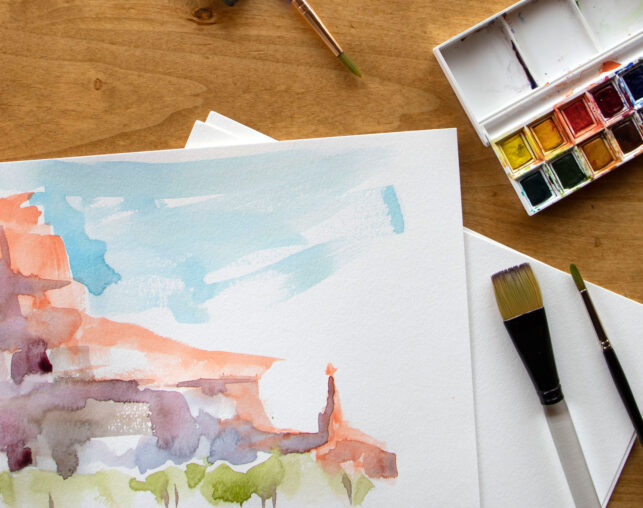 watercolors on paper with paint and brushes scattered around